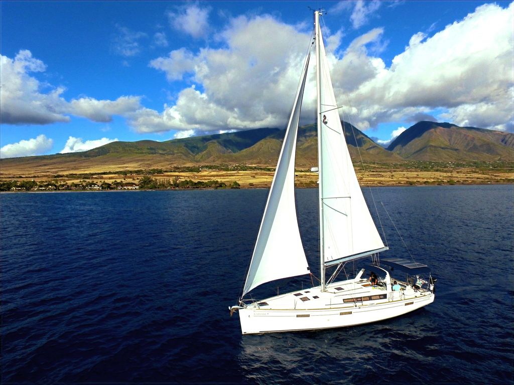 SV Kainani under full sail off West Maui, the mountains behind